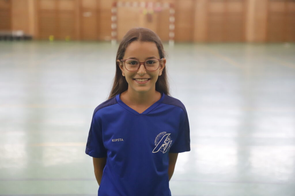 Niña sonriente con camiseta de fútbol sala en un pabellón deportivo