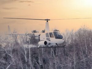 Helicóptero Robinson R44 volando en un paisaje nevado al atardecer