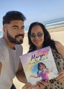 Juan Heredia Urbano y una mujer sosteniendo el libro Marypí en la playa