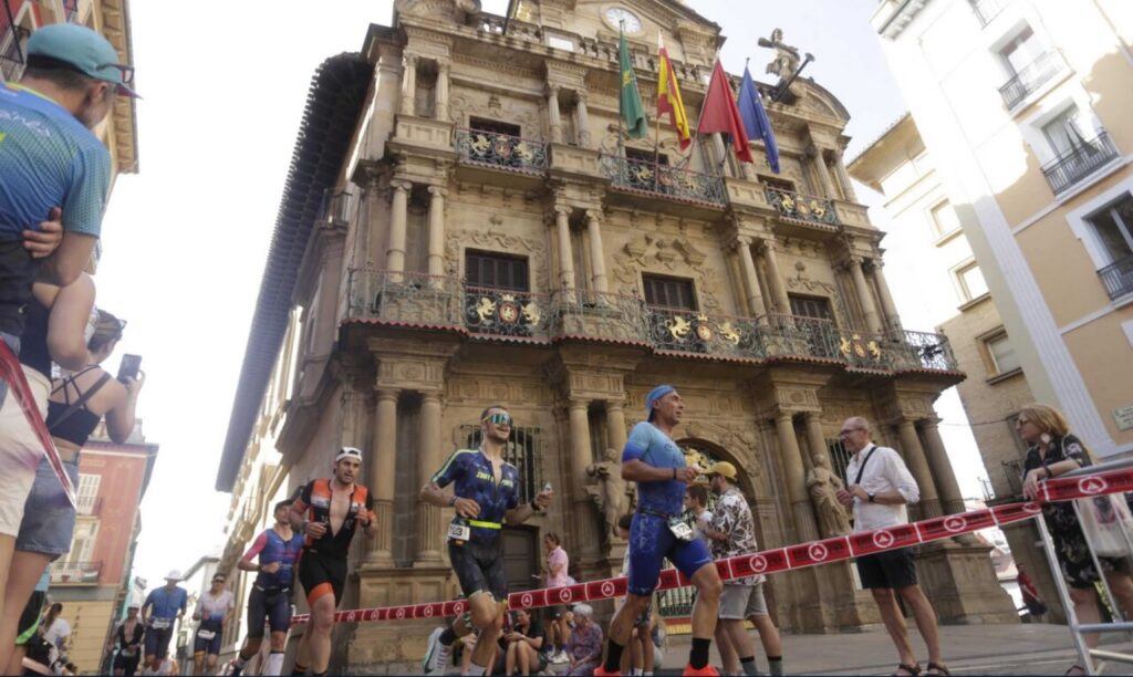 Triatletas corriendo frente al Ayuntamiento de Pamplona durante una competición.