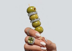 Mano sosteniendo un pincho con aceitunas y anillos brillantes