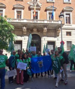 Grupo de personas en una manifestación con banderas verdes y pancartas.