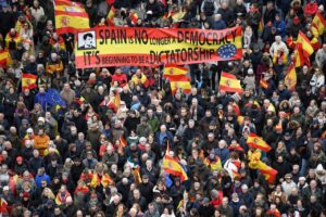 Multitud de personas en una manifestación con pancartas y banderas de España.