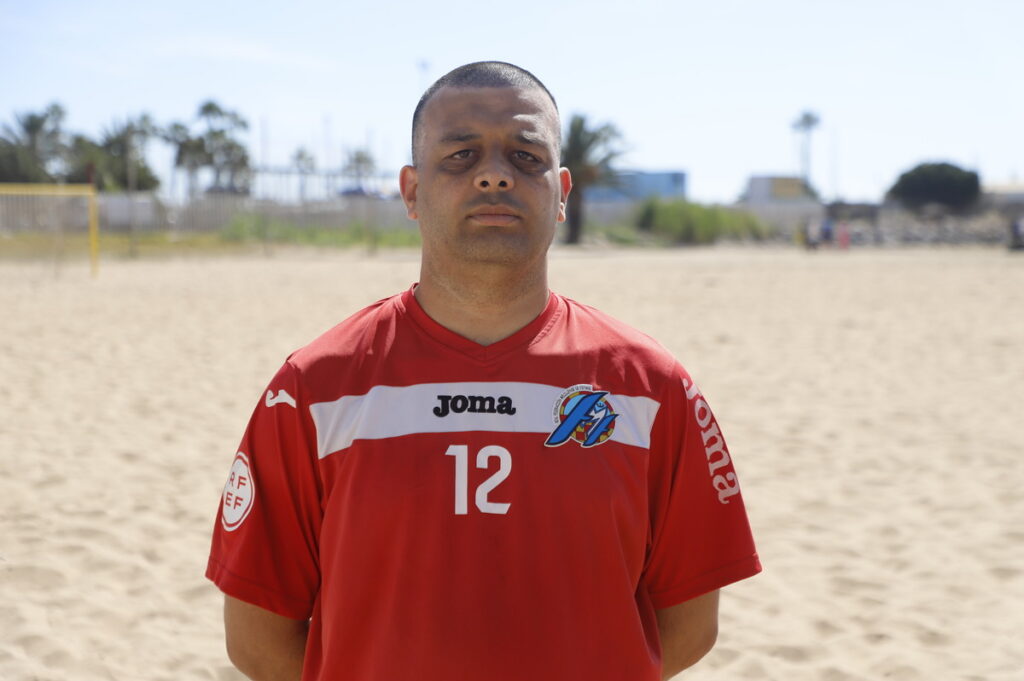 Jugador de fútbol playa de Melilla en camiseta roja en la playa