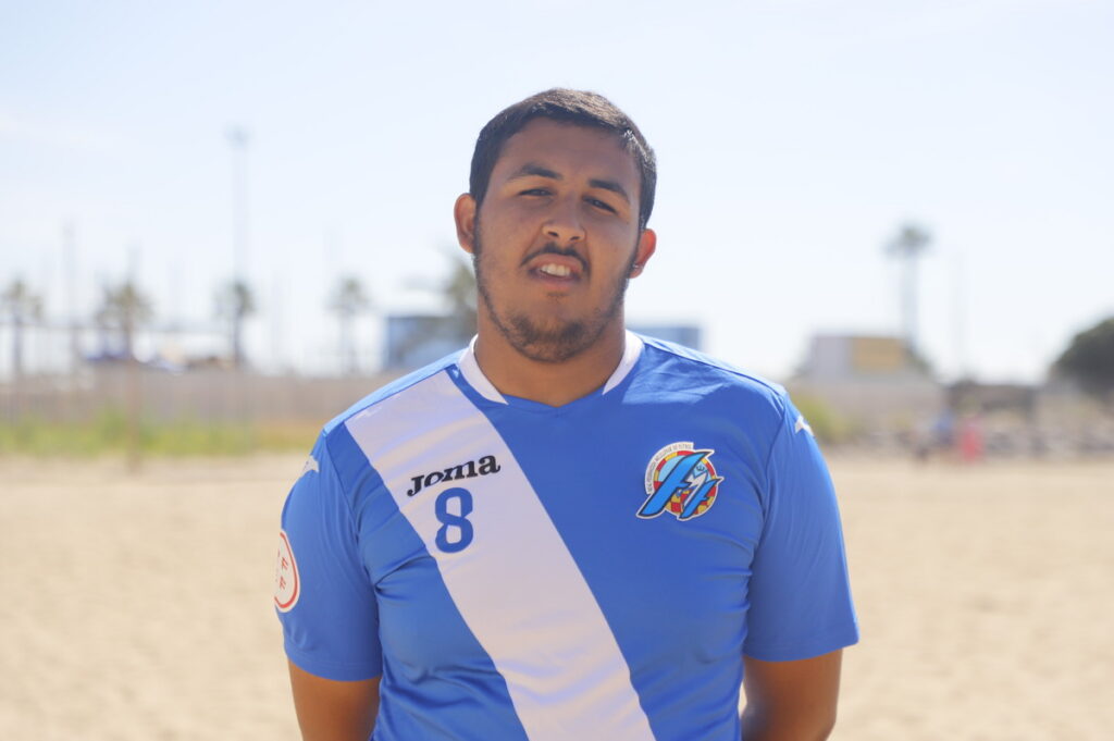 Jugador de fútbol playa de Melilla con camiseta azul en la playa
