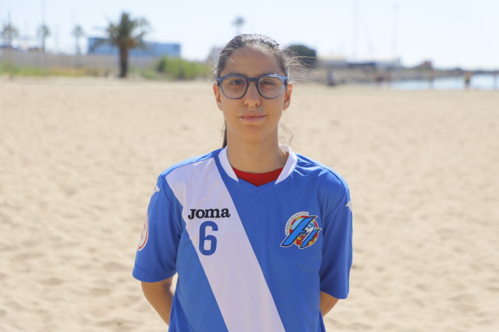 Jugadora de fútbol playa Zhara en la arena con camiseta azul