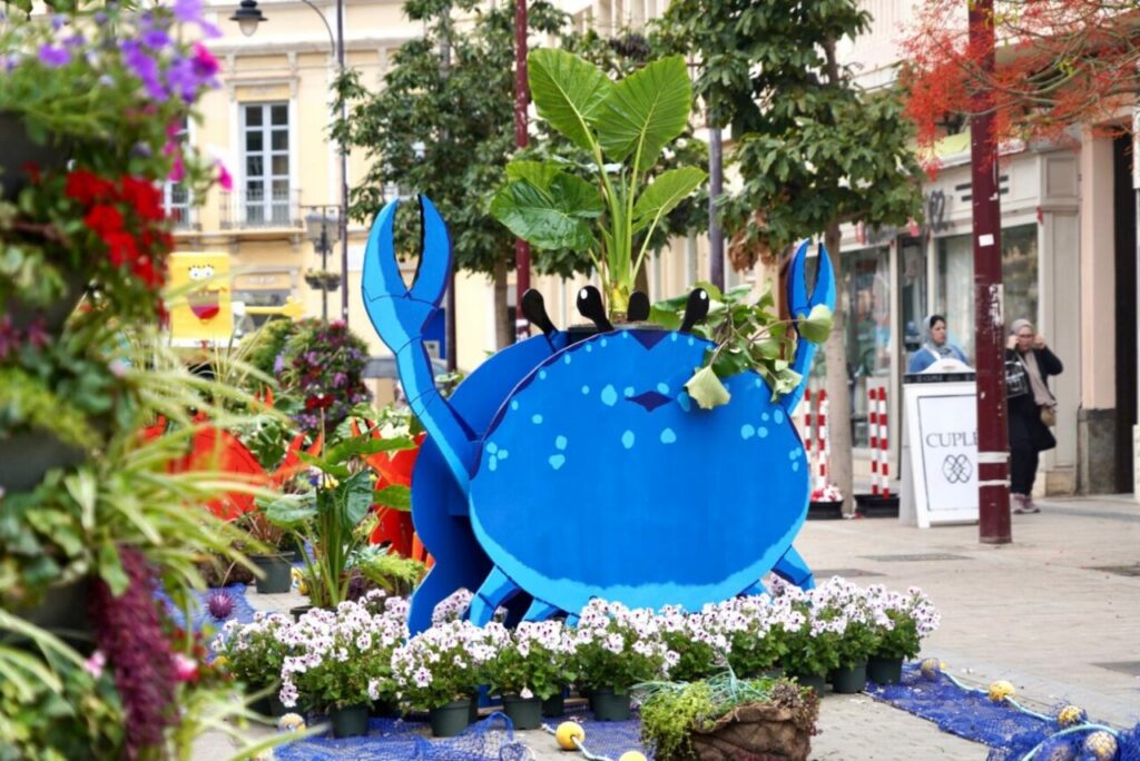 Escena floral en Melilla con un cangrejo azul decorativo y plantas