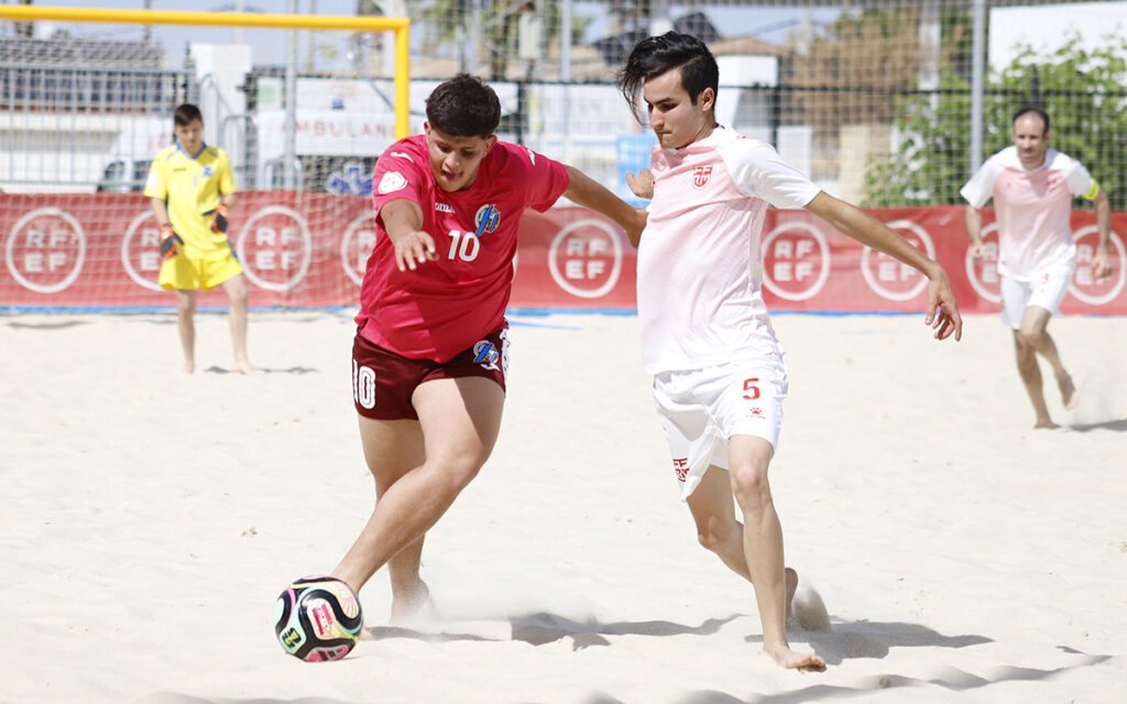 Jugadores de fútbol playa compitiendo en la arena durante un partido.