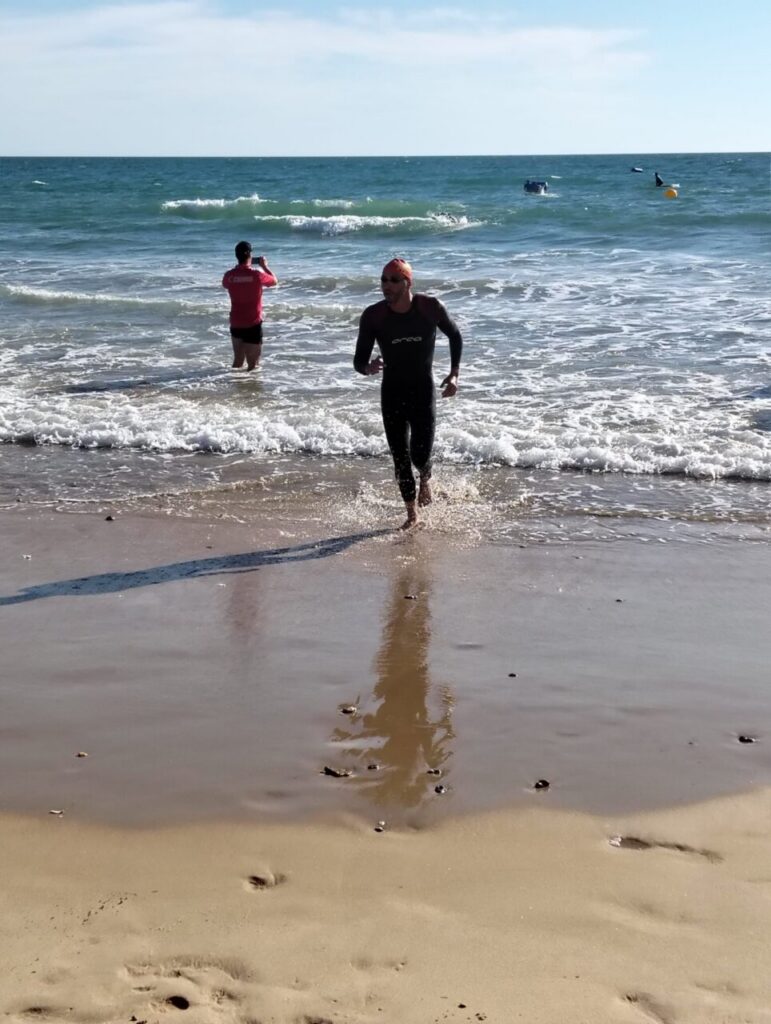 Nadador corriendo en la playa tras una competición de aguas abiertas