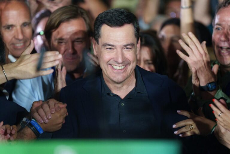 Juanma Moreno sonriendo en un evento político con apoyo de la multitud