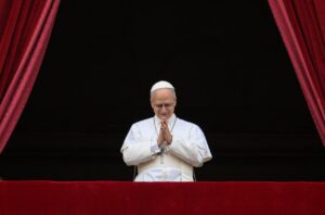 El Papa XIV en una ceremonia con manos juntas y sonriendo.
