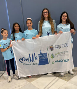 Gimnastas del Club Virka Melilla sosteniendo una bandera en un evento deportivo