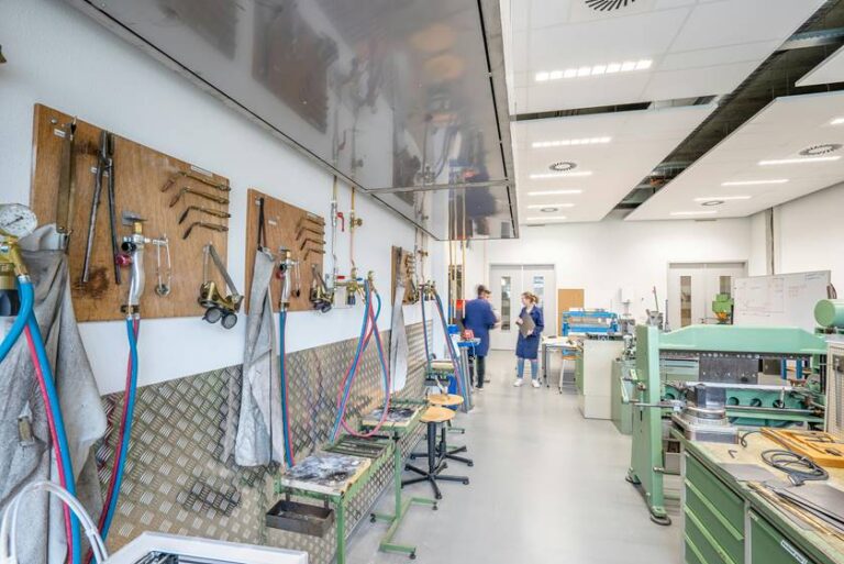 Aula de formación profesional con herramientas y estudiantes trabajando