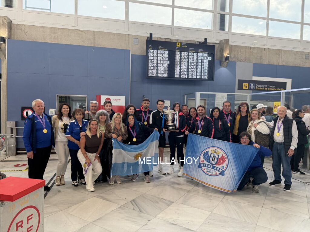 Jugadores y aficionados del Melilla Torreblanca CF celebrando su victoria en el aeropuerto.
