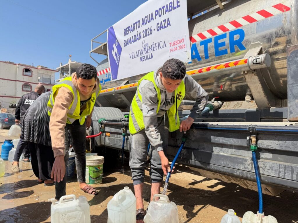 Relief workers in bright vests filling water containers from a tanker in Gaza during Ramadan relief effort.