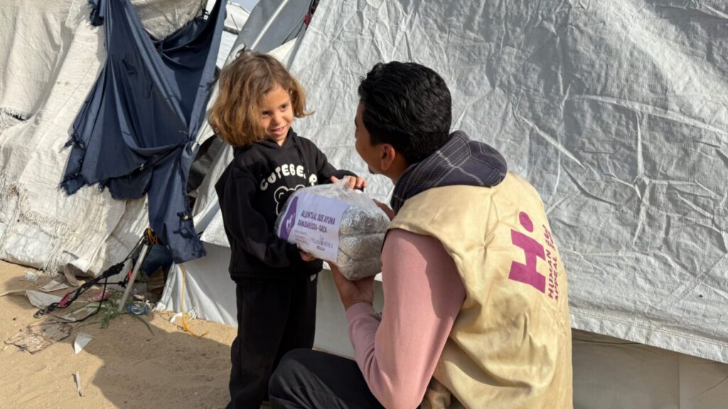 Niño recibiendo comida en un campamento de Gaza durante una campaña humanitaria.