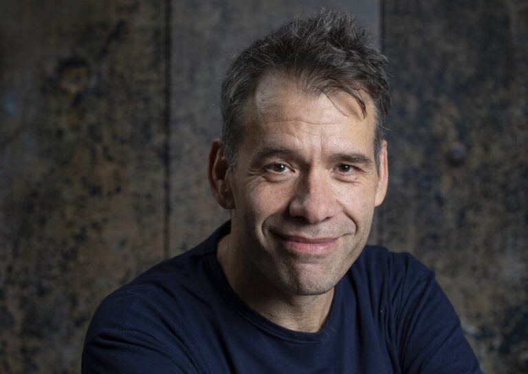 Retrato del periodista Rubén Amón sonriendo en un fondo texturizado