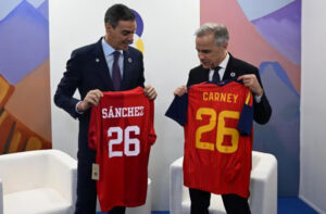 Pedro Sánchez y Mark Carney sosteniendo camisetas durante reunión en Armenia