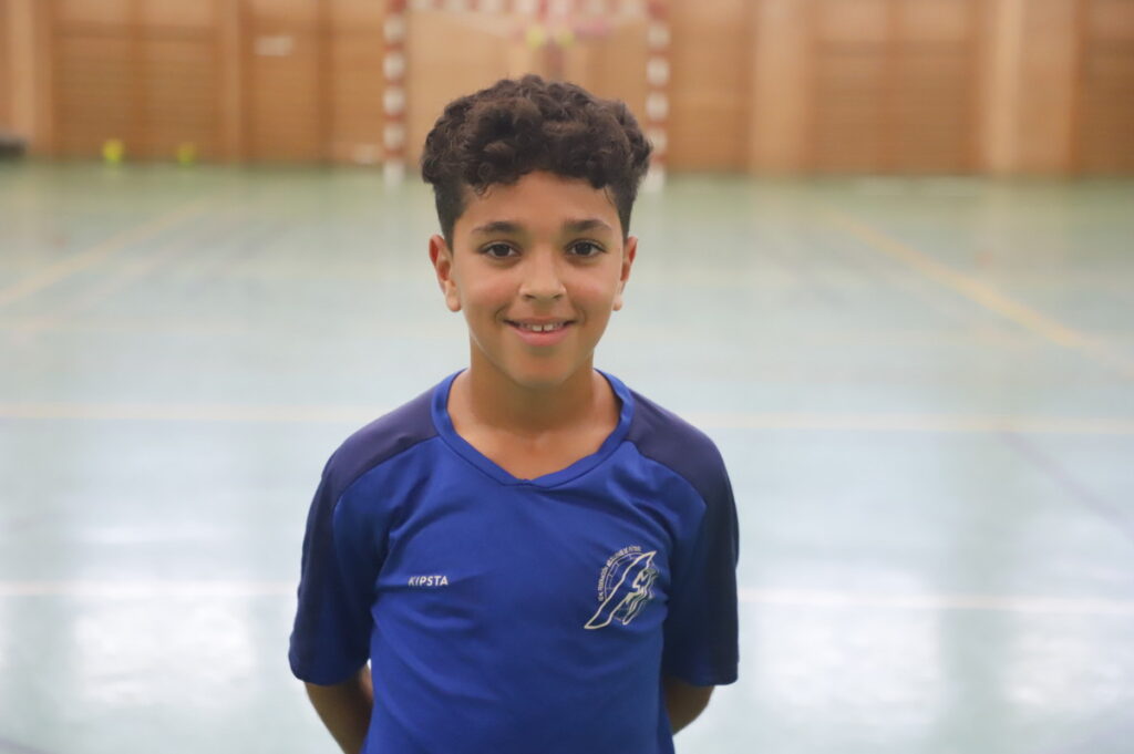 Niño sonriente con camiseta de fútbol sala en un pabellón deportivo