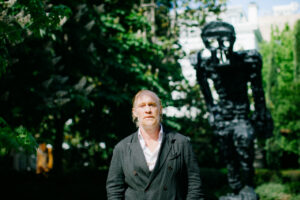 Escultor Thomas Houseago en el jardín de Banca March junto a su escultura.