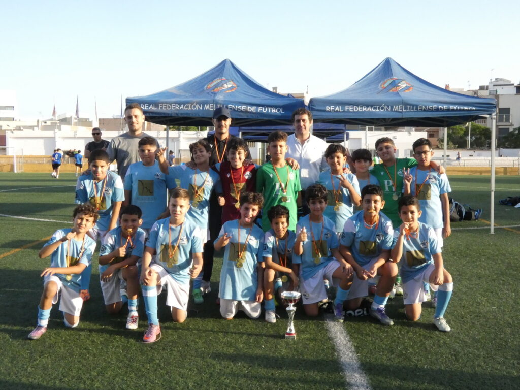 Niños alevines celebrando en el torneo de fútbol con medallas y trofeos