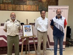 Tres hombres posando junto a un cartel de la VI Regata de Defensa en Melilla