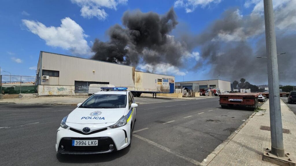 Vehículo policial frente a naves industriales en llamas en Melilla