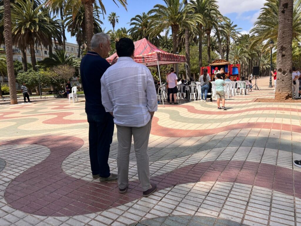 Dos hombres conversando en un parque durante un evento familiar de teatro