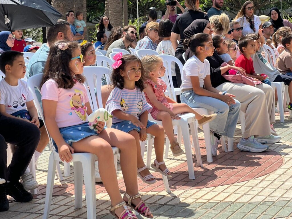 Niños sentados en sillas durante una representación teatral al aire libre