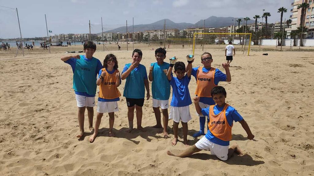 Grupo de niños en la playa jugando al fútbol