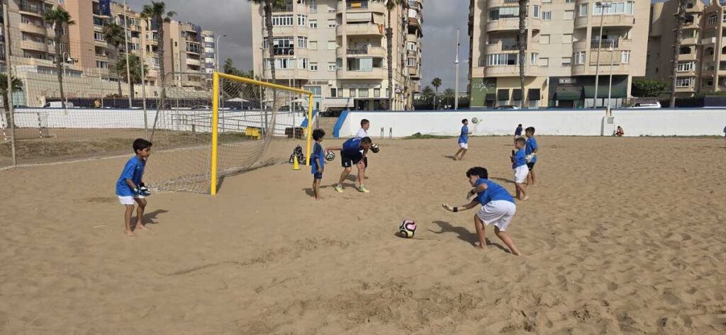 Niños jugando al fútbol en la playa con una portería