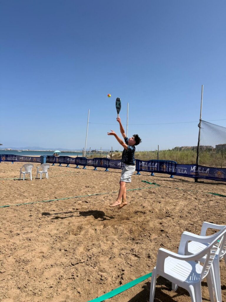 Jugador de tenis playa realizando un saque en la arena