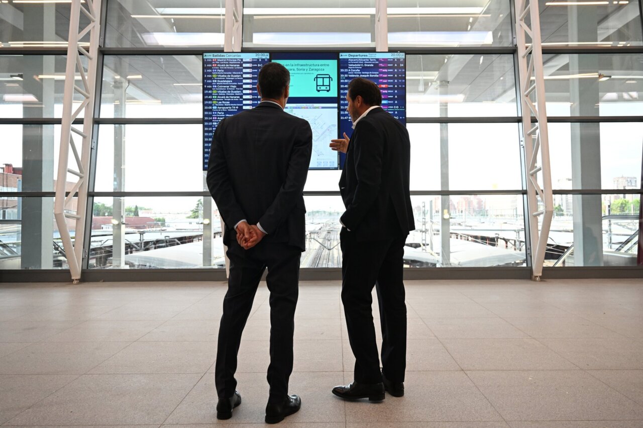 Dos hombres en trajes observando pantallas en la estación de Chamartín