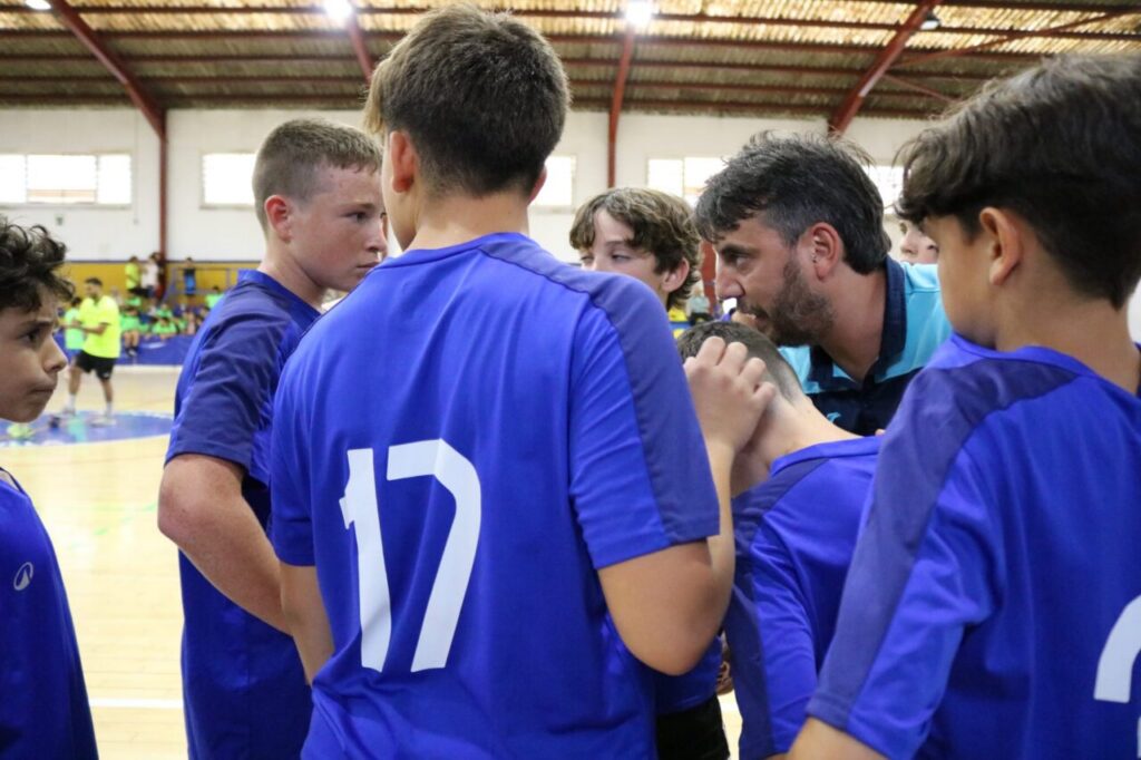 Entrenador hablando con jóvenes jugadores de balonmano en el Pabellón Municipal.