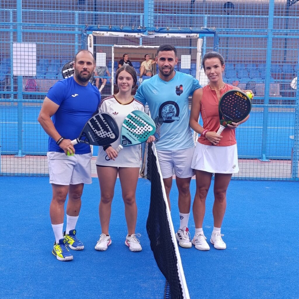 Four padel players pose on a blue court holding rackets.