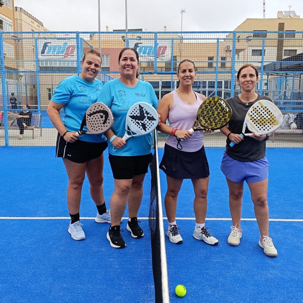 Cuatro jugadoras de pádel posando en la cancha con palas