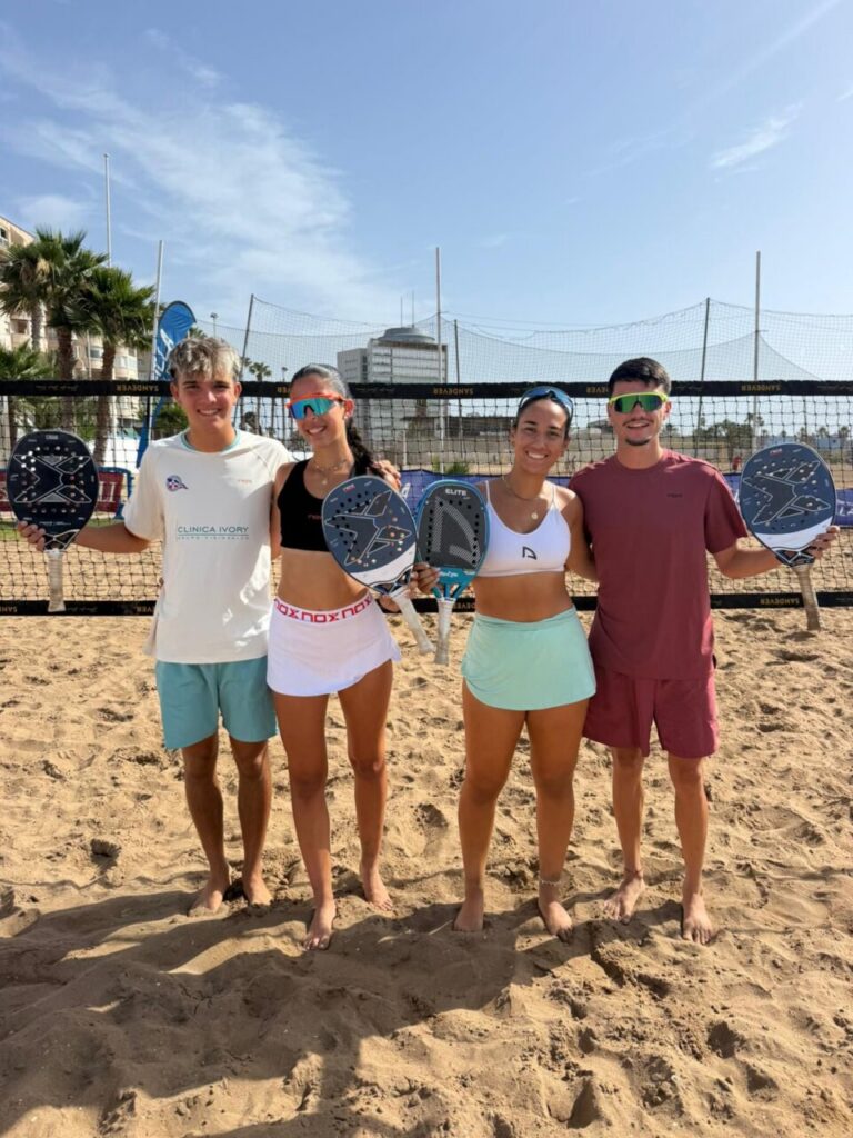 Cuatro jugadores de tenis playa posando en la arena con palas