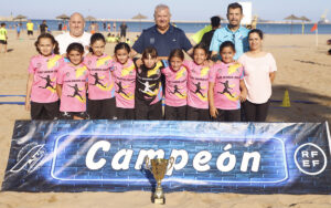 Equipo de niñas campeonas con trofeo en la playa