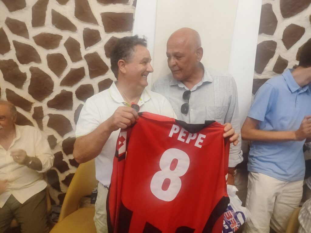 Dos hombres sonríen mientras sostienen una camiseta con el nombre Pepe