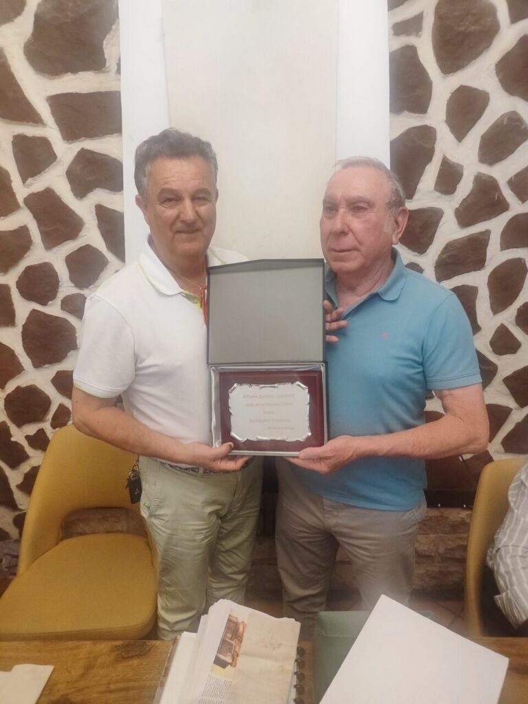 Dos hombres sosteniendo un reconocimiento en un evento de homenaje a Pepito.