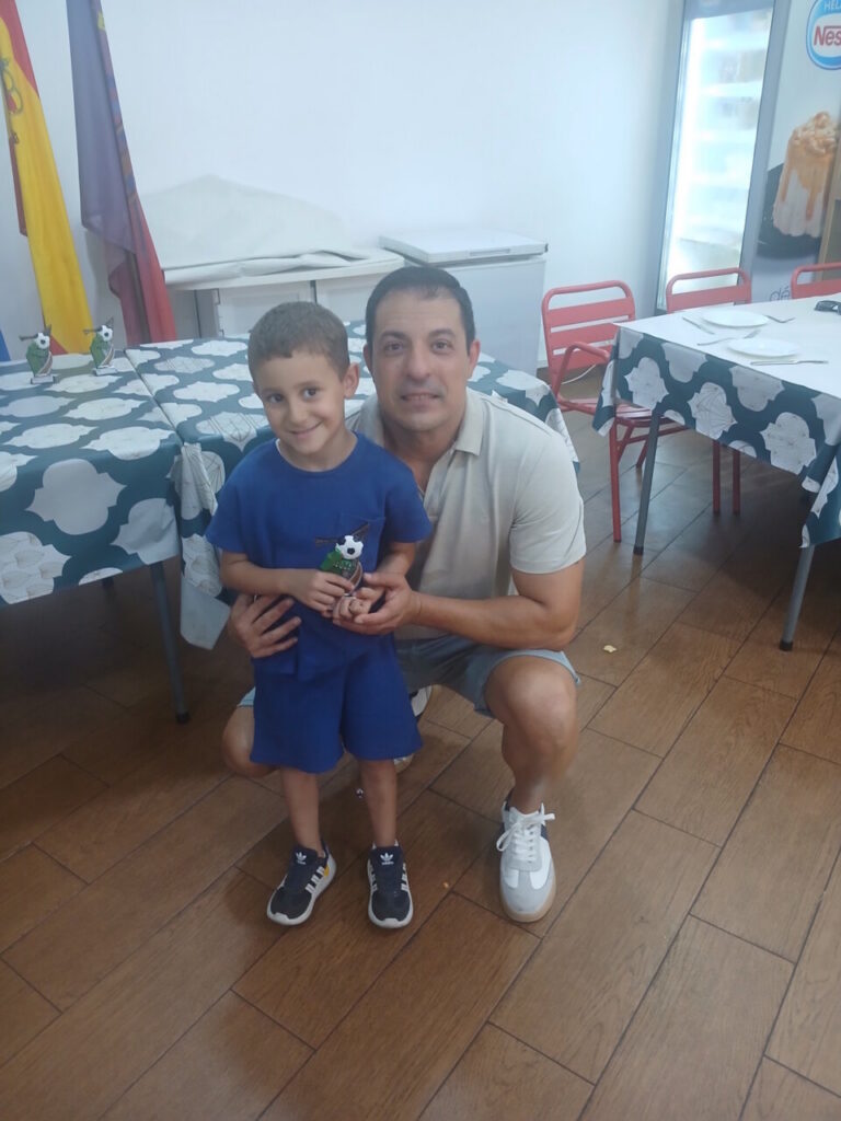 Un niño y un adulto sosteniendo un trofeo en una celebración escolar