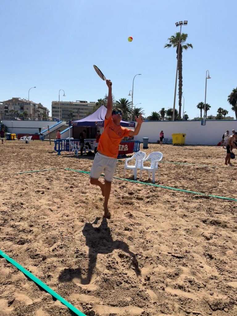 Jugador de tenis playa lanzando la pelota en la arena