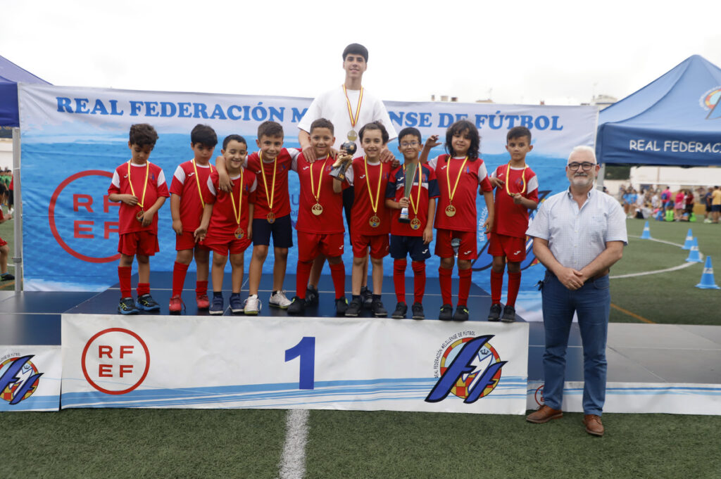 Niños en un podio recibiendo medallas en un torneo de fútbol