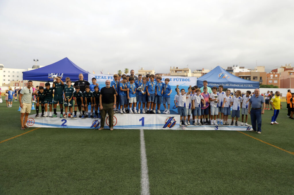 Niños en un podio durante la premiación de un torneo de fútbol infantil en Melilla.