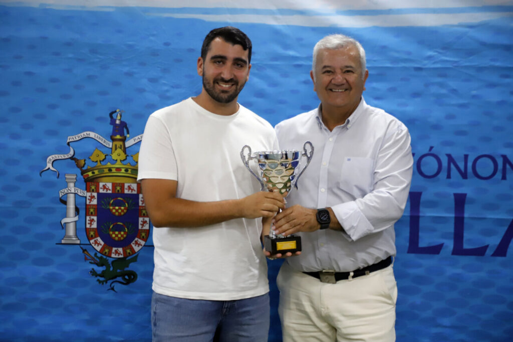 Dos hombres sosteniendo un trofeo en un evento deportivo en Melilla