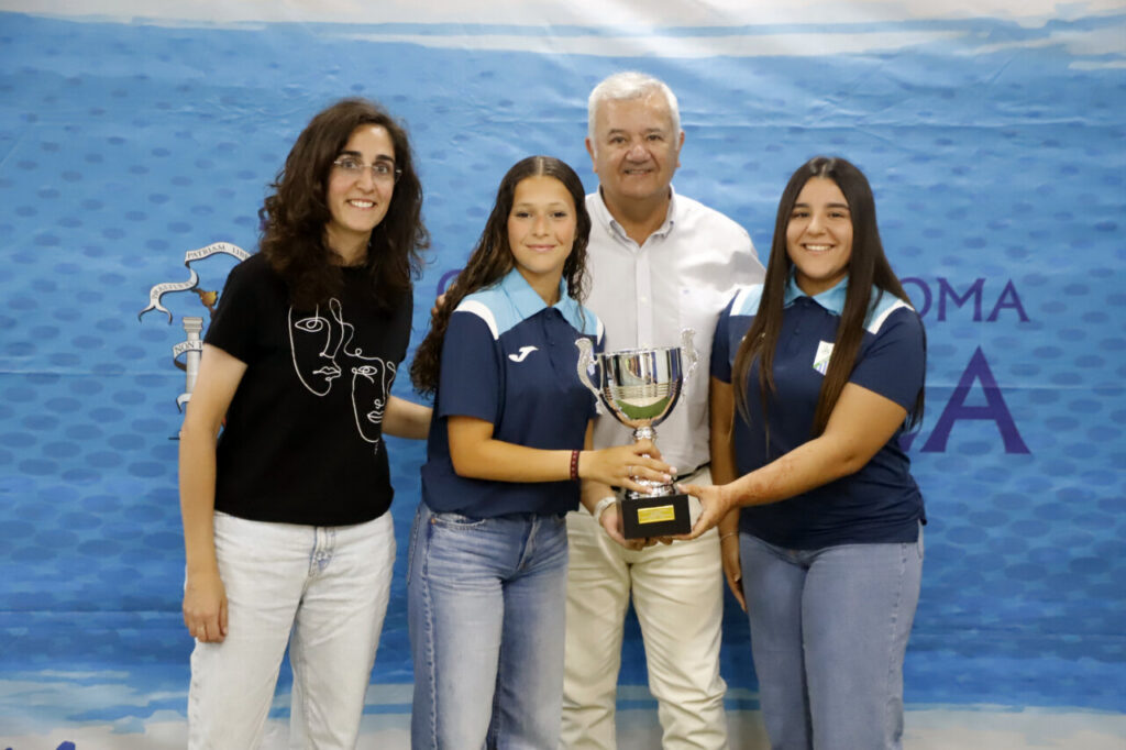 Cuatro personas sosteniendo un trofeo en un evento deportivo en Melilla.