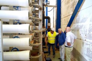 Tres personas observando el proceso de construcción de una desaladora