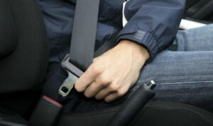 Persona abrochando el cinturón de seguridad en un vehículo