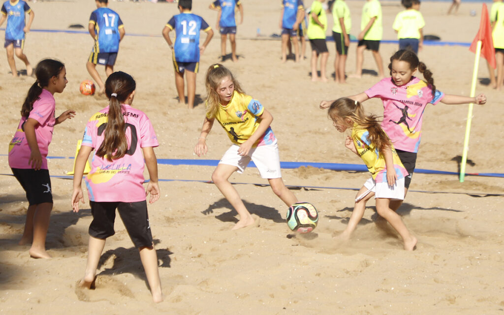 Niñas jugando al fútbol en la playa durante un torneo