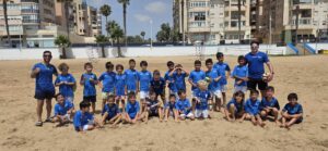 Grupo de niños en la playa con camisetas azules de fútbol